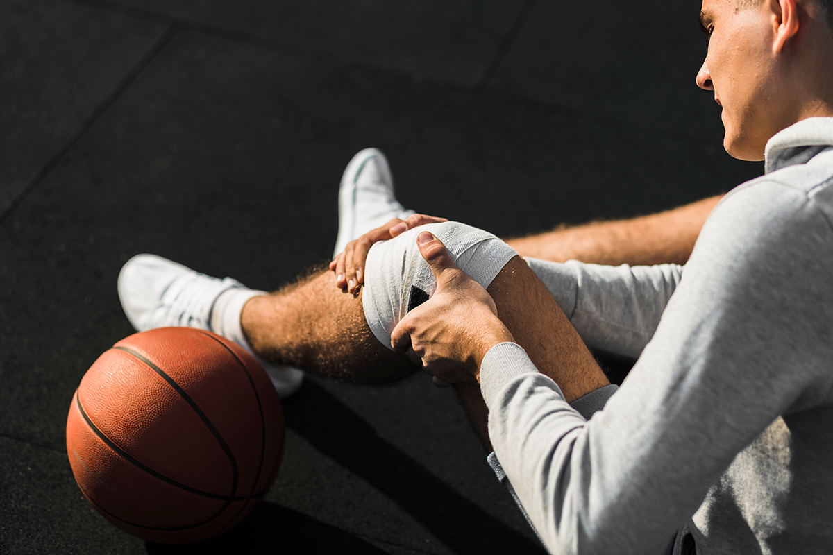 basketball-player-applying-bandage-on-knee.png